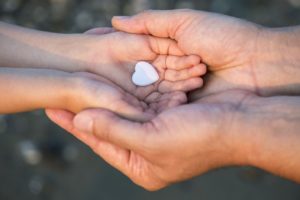 Close up of child and man hands with heart